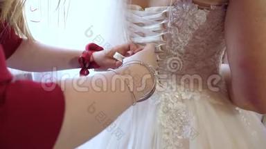 新娘正在准备婚礼。 婚纱特写.. 伴娘用蝴蝶结向婚纱鞠躬。 球球